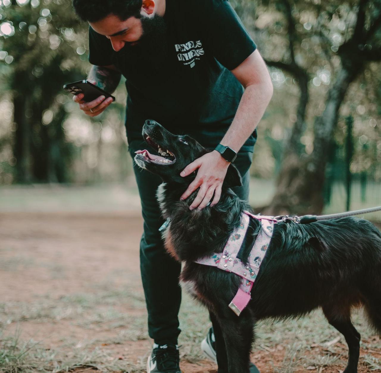 A man plays with his dog using a smartphone in a park in São Paulo, Brazil.