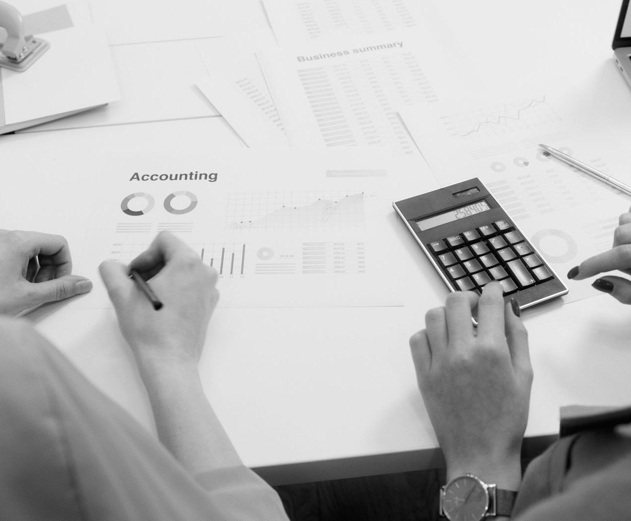 Black and white office scene featuring accounting documents, calculator, and laptops.