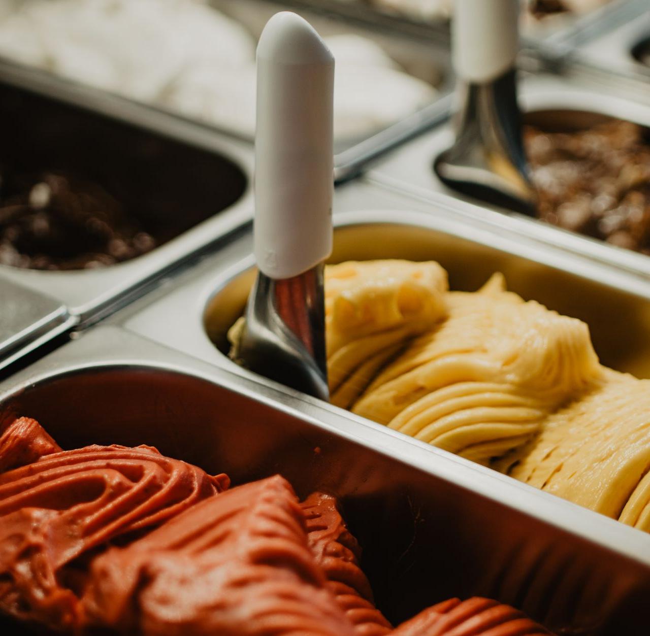 A vibrant display of colorful gelato flavors in metal trays at an ice cream shop.