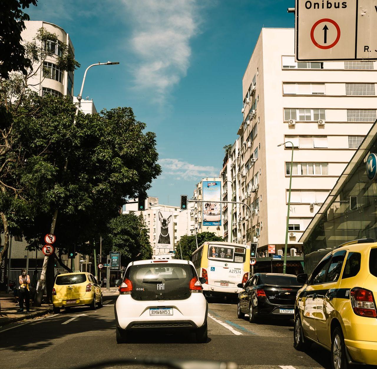 Capture of a lively street in Rio de Janeiro, featuring traffic and pedestrians on a sunny day.