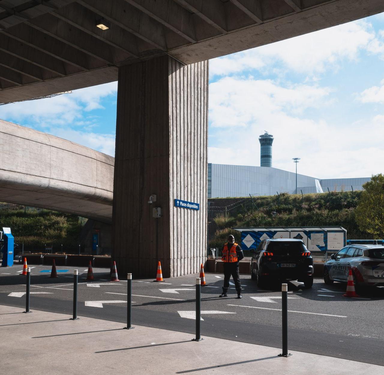 A bustling airport entrance with vehicles and people in Roissy, France.