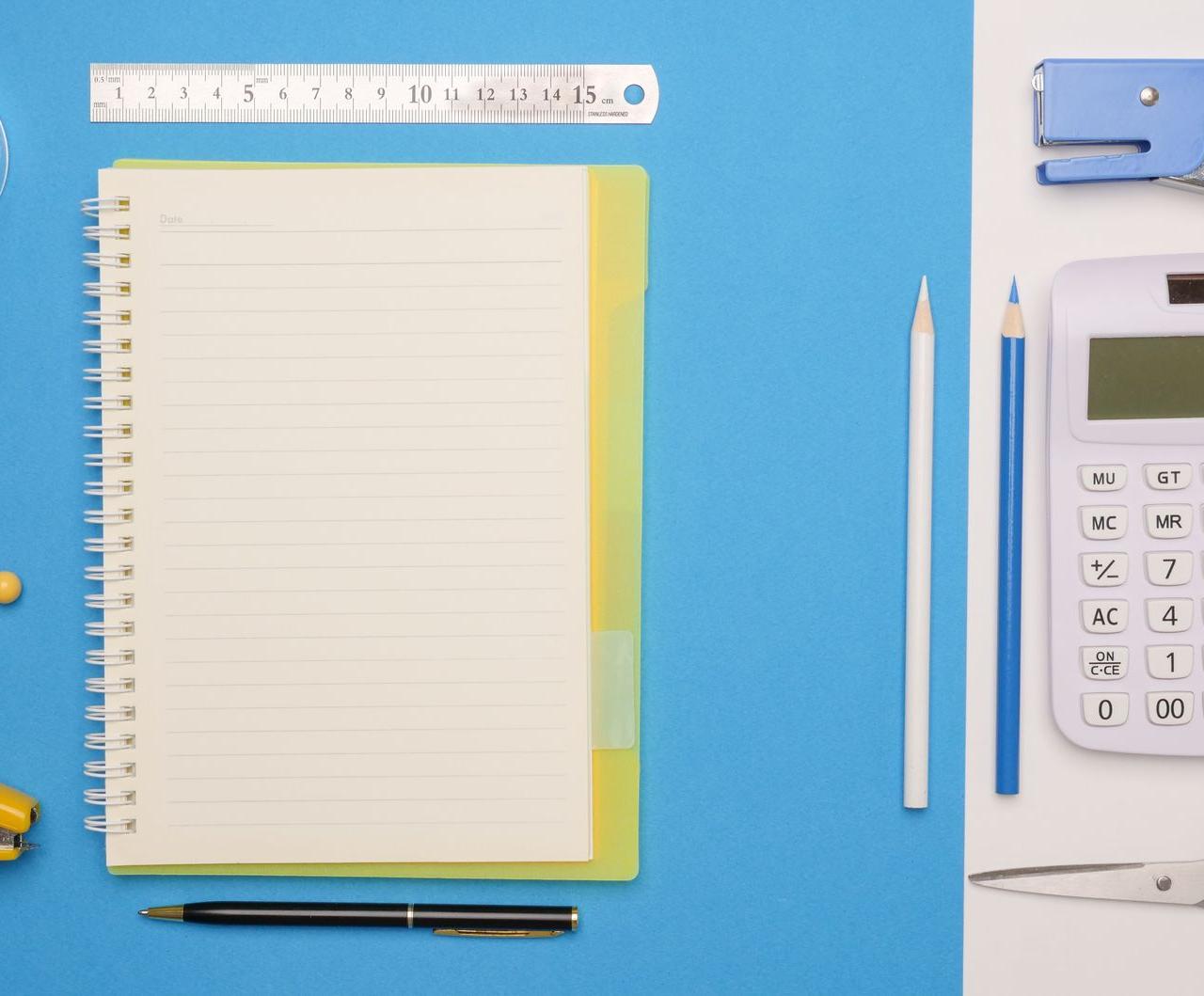 Overhead view of stationery items arranged neatly on blue surface.