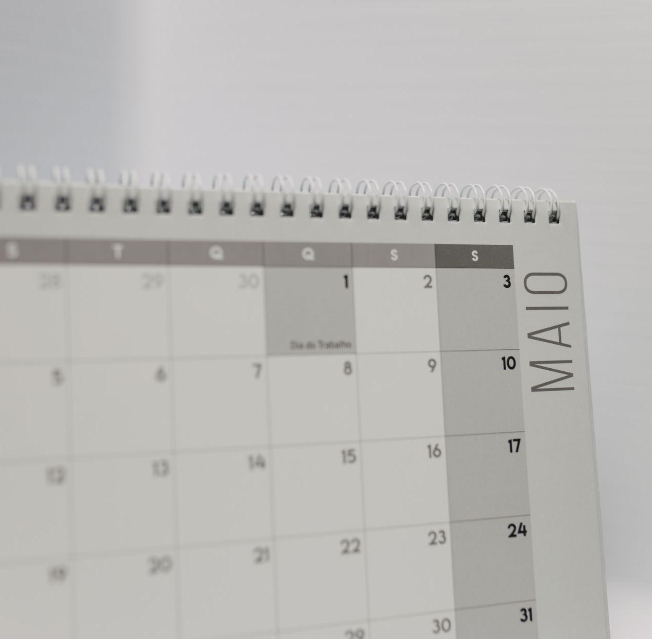 Spiral-bound calendar showing May with focus on weekdays in Portuguese.