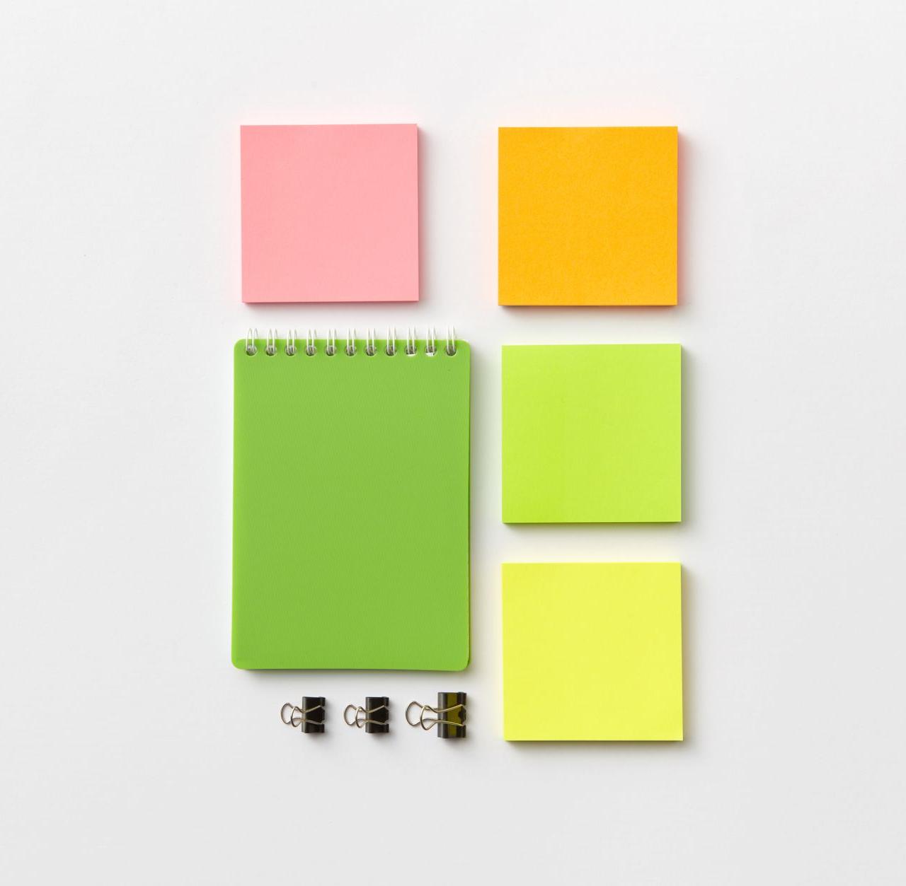 Top view of colorful stationery items including notepad and sticky notes on a white surface.