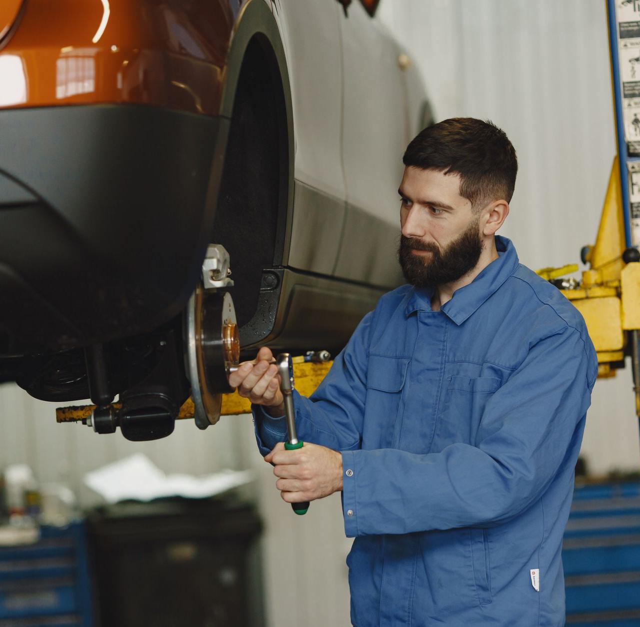 Professional mechanic working on car maintenance in an automotive garage.