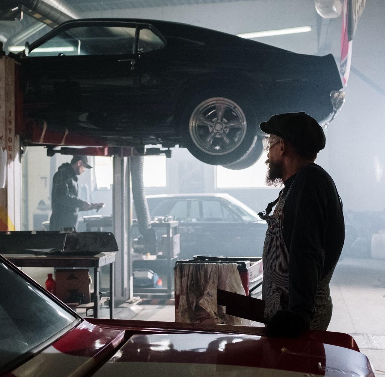 Mechanics busy at work in a dimly lit auto repair garage with a raised car.