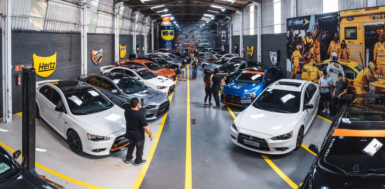 A vibrant scene of a car enthusiast gathering at Vila Nair, showcasing a variety of vehicles indoors.