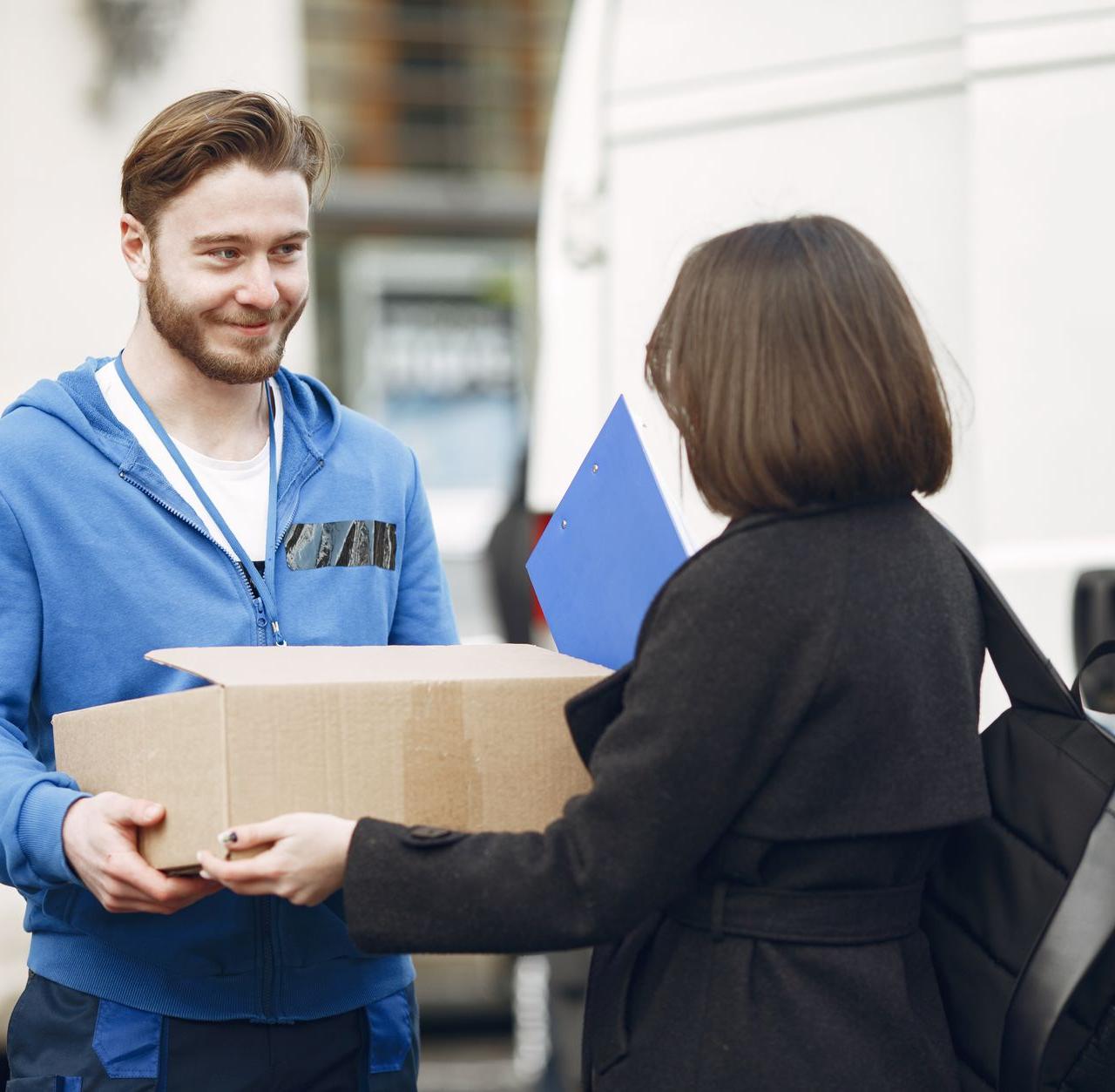 Candid moment of a deliveryman handing a package to a woman outside by a van.