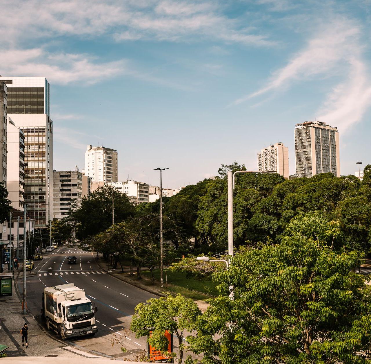 A bright urban scene in Rio de Janeiro with trees and modern buildings lining the street.