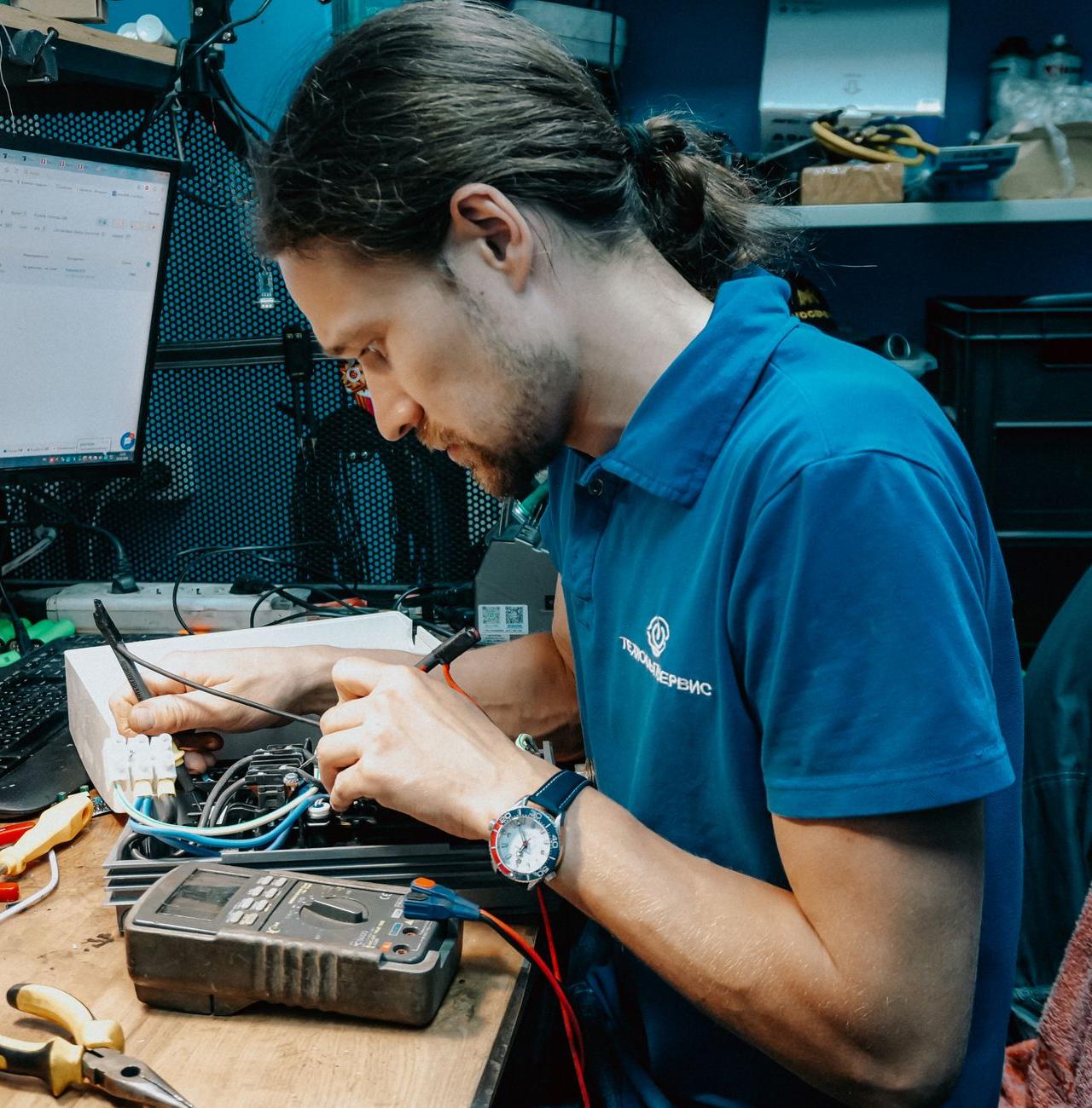 Focused technician mending electronics with tools in a modern workshop setting.