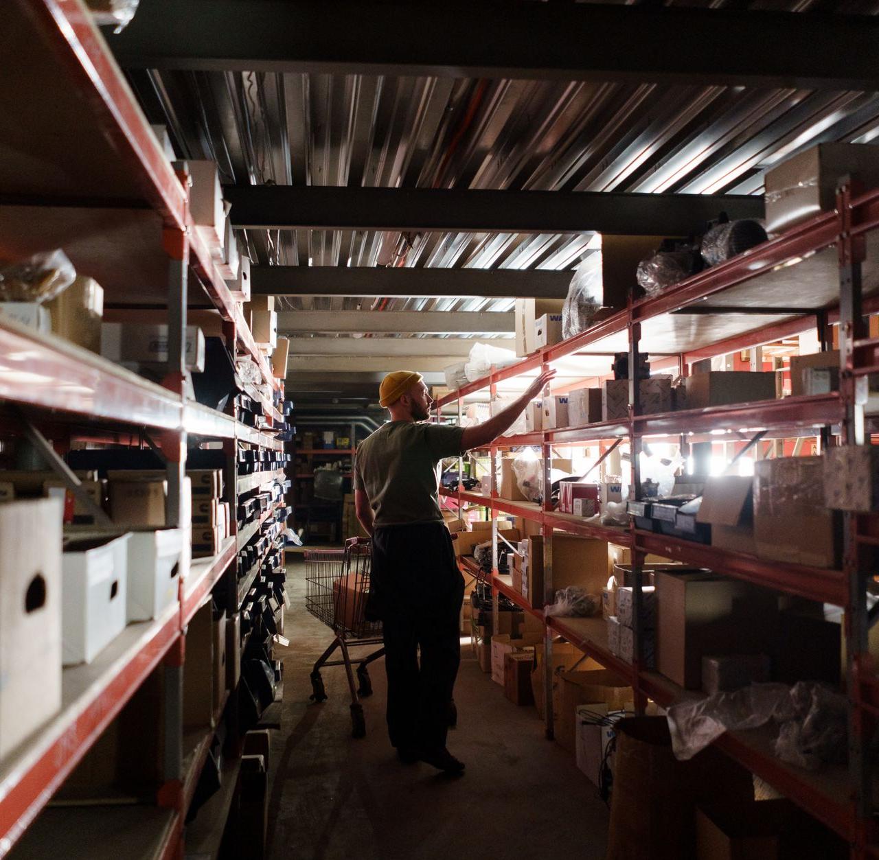A warehouse worker arranging inventory on metal shelves in a storage facility