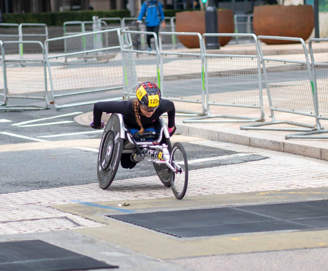 A dedicated athlete competes in a marathon using a racing wheelchair on city streets.
