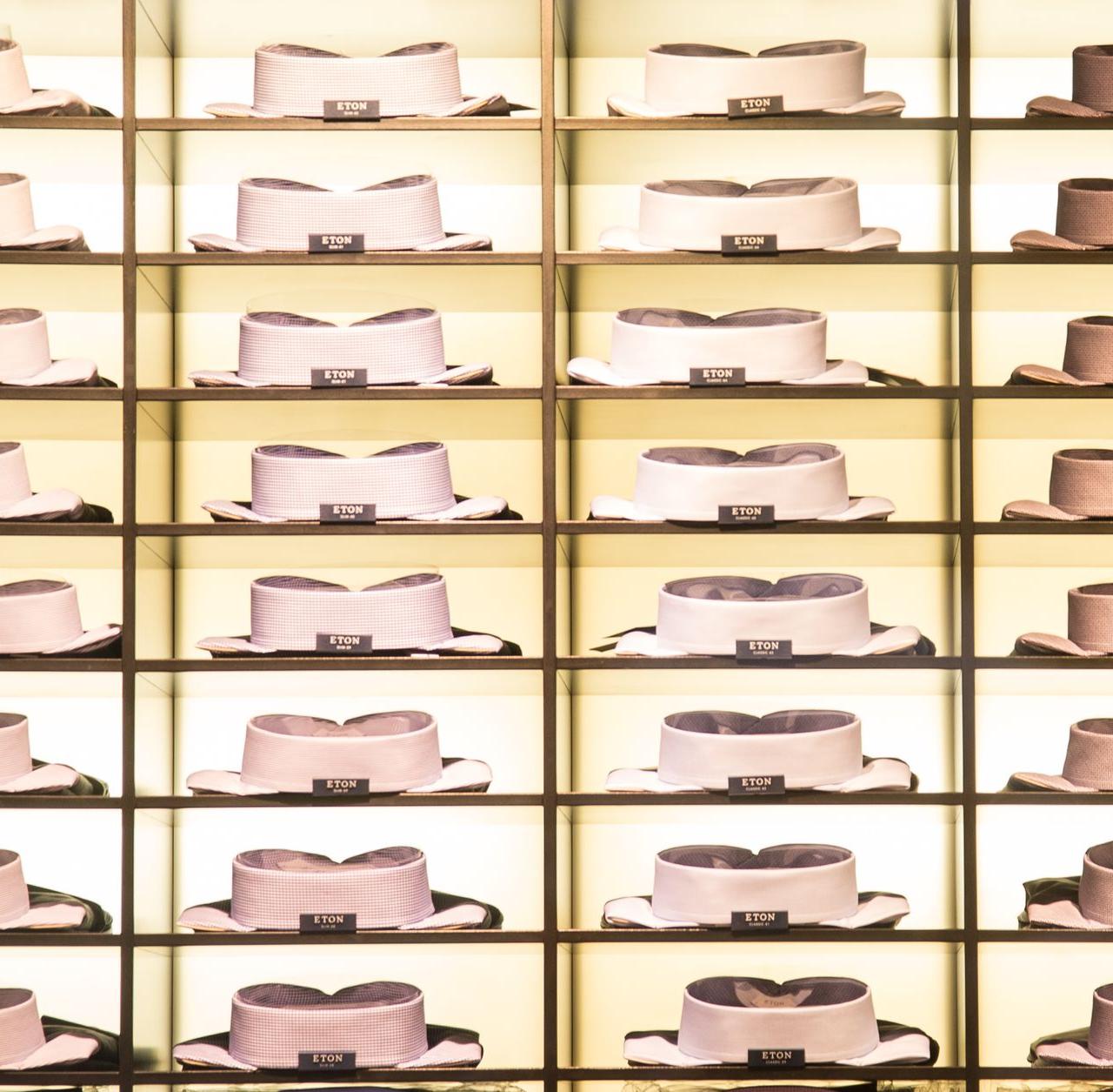 Organized collection of neatly stacked dress shirts showcased on shelves in a stylish fashion store.