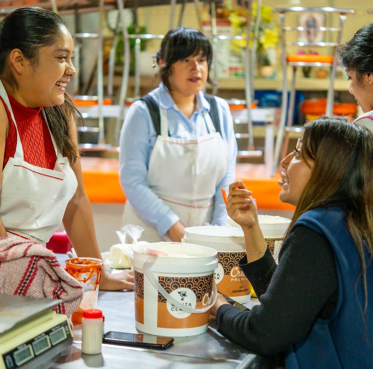 Women interacting joyfully in a Ciudad de México kitchen, promoting teamwork and culture.