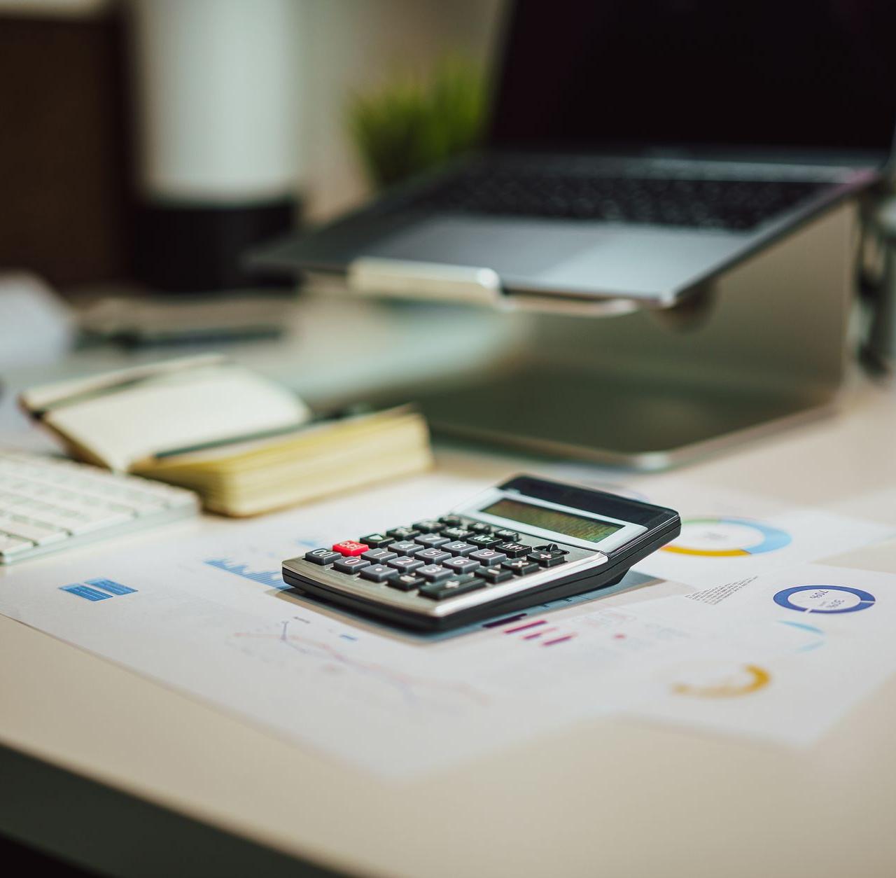 A modern workspace with a laptop, calculator, and documents on a desk, perfect for finance tasks.