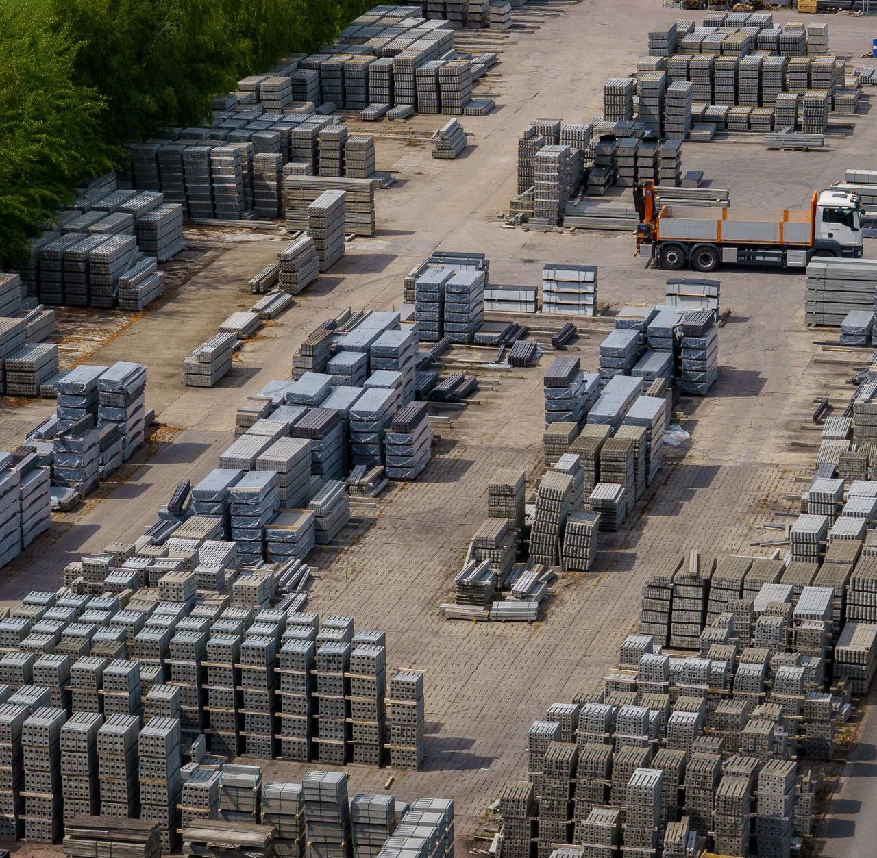 Aerial shot of a vast industrial yard with stacked bricks and a loading truck, captured on a clear day.