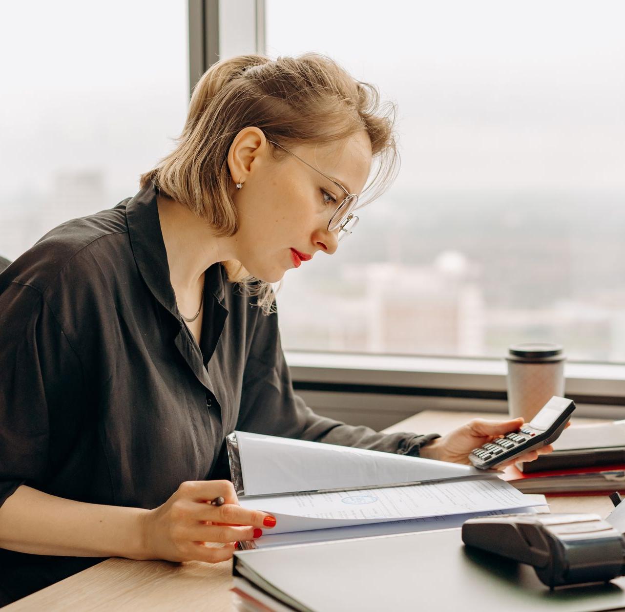 Woman accountant calculating financial documents at office desk.