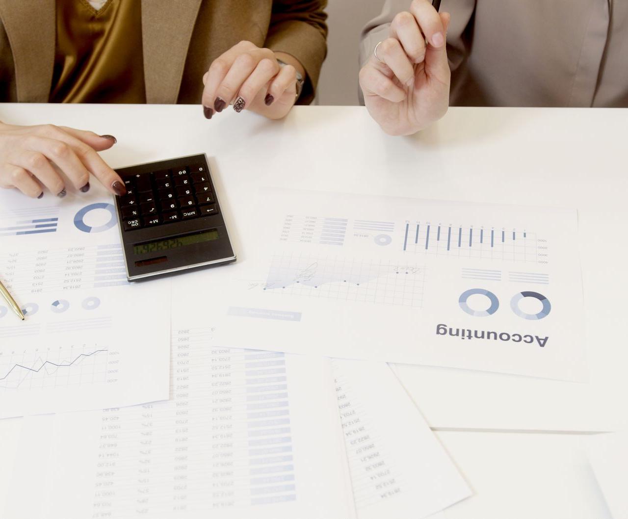 Two professionals analyzing financial documents with a calculator.