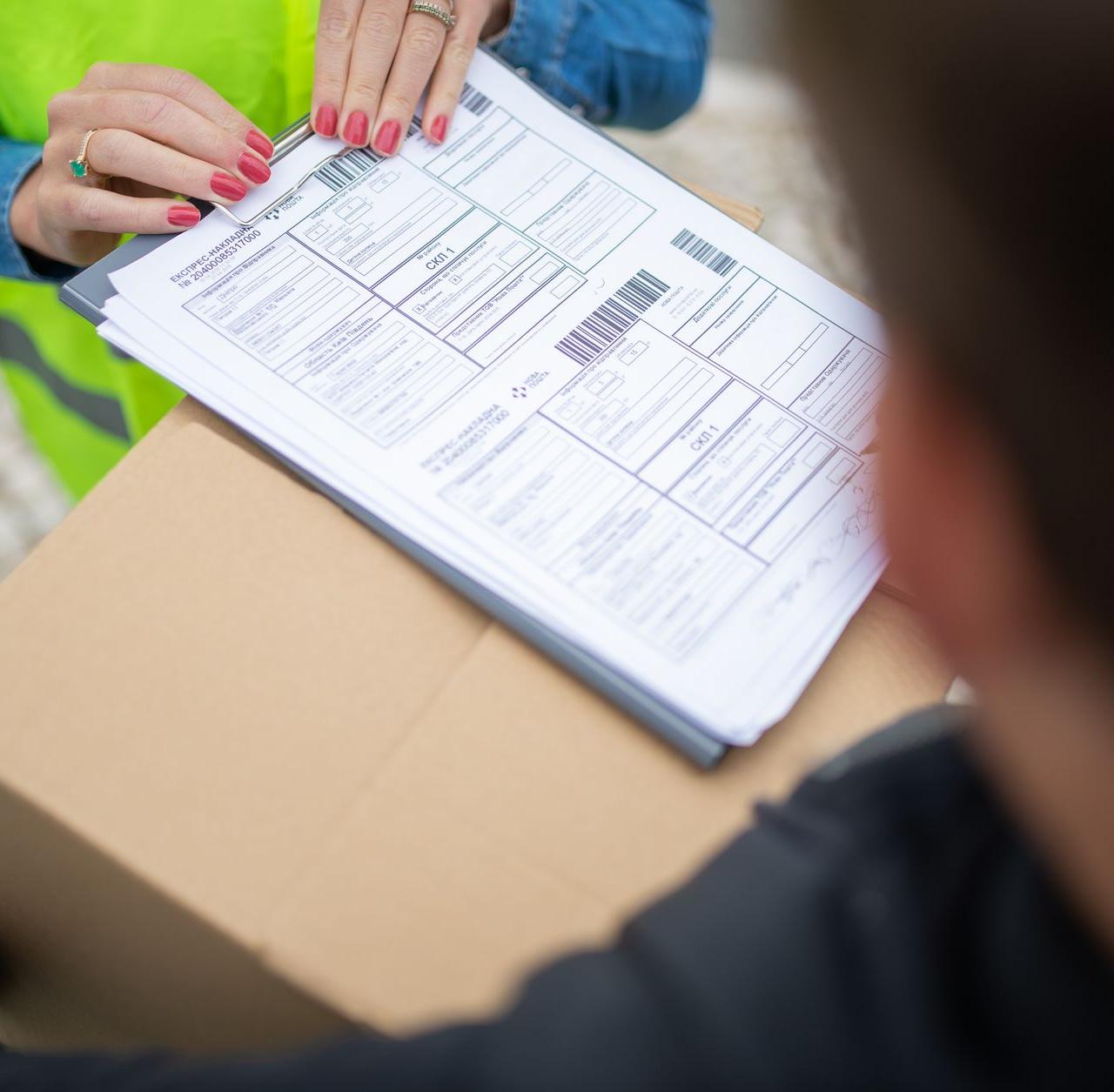 Courier hands over a package for delivery with signing of receipt documents.