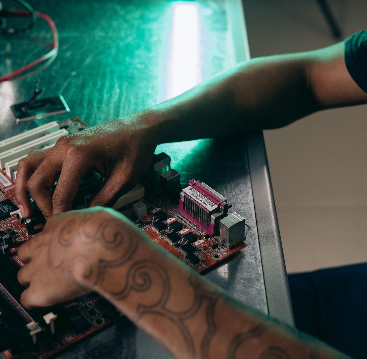 Close-up of person assembling a computer motherboard, showcasing a tattooed arm and tech innovation.
