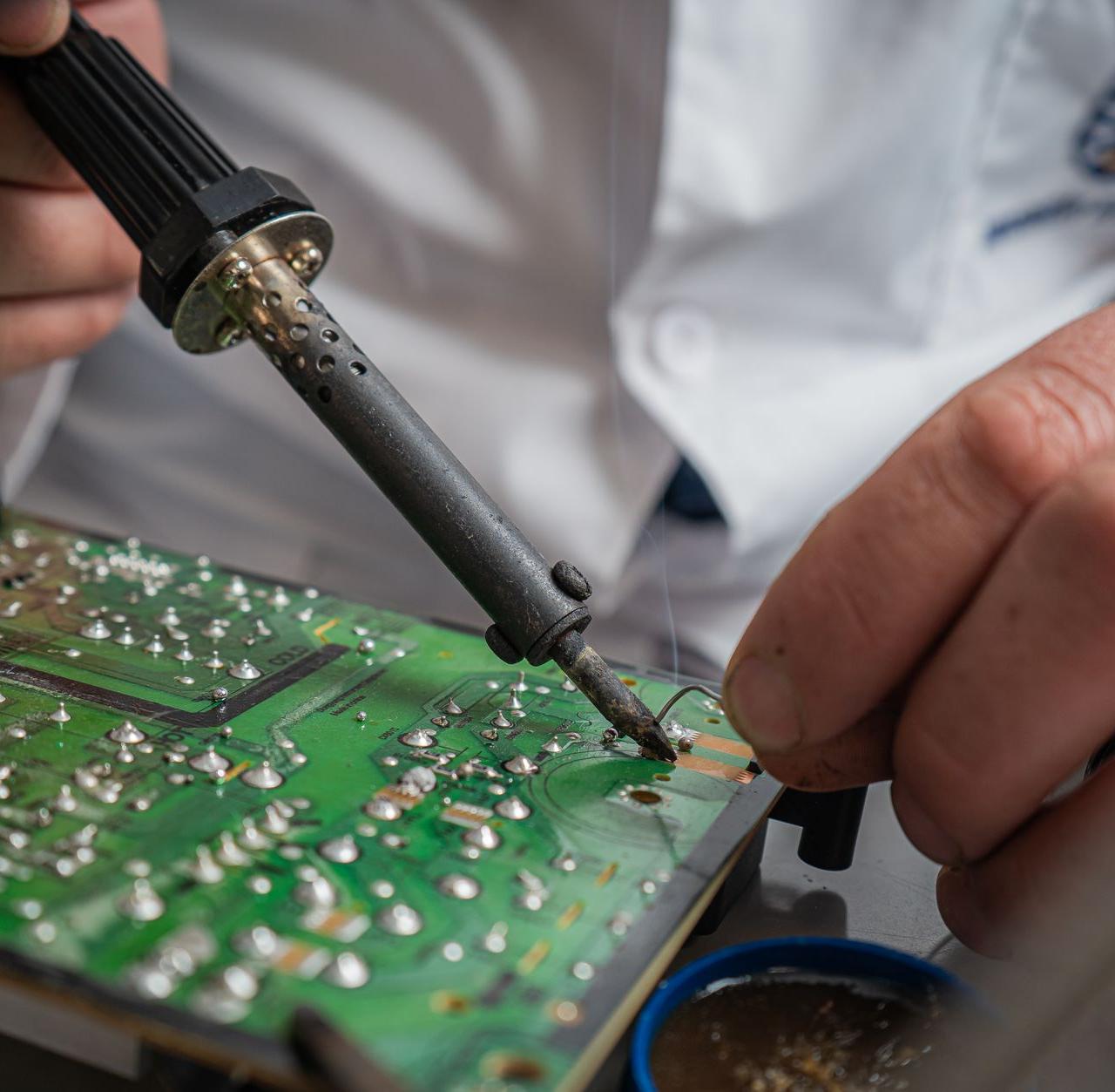 Technician performing precise soldering on a circuit board for electronics repair.
