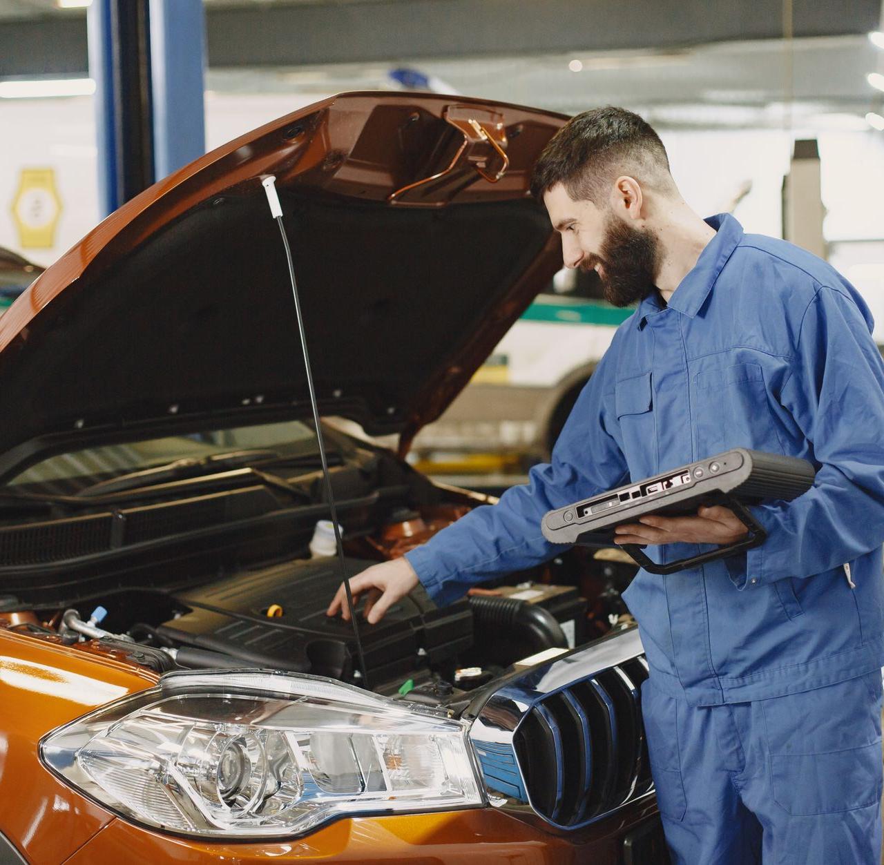Skilled mechanic working on car engine diagnostics in a modern garage.
