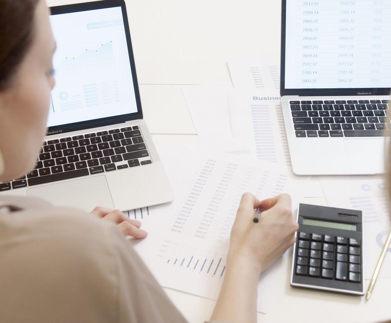 Two people analyzing business data on laptops with charts and graphs.
